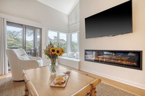 A modern living room with a fireplace, a large window, and a comfortable seating area.