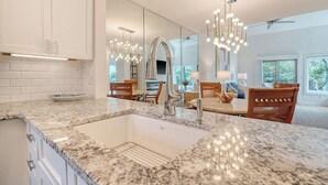 Una cucina con una grande isola, mobili bianchi e un lampadario moderno.