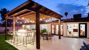An outdoor patio with a pergola, bar area, and dining space. - Sunburst Estate - Pool - Hot Tub - Tons of Games! (Scottsdale)
