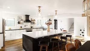 A modern kitchen with a large island, bar stools, and pendant lighting. - Sunburst Estate - Pool - Hot Tub - Tons of Games! (Scottsdale)