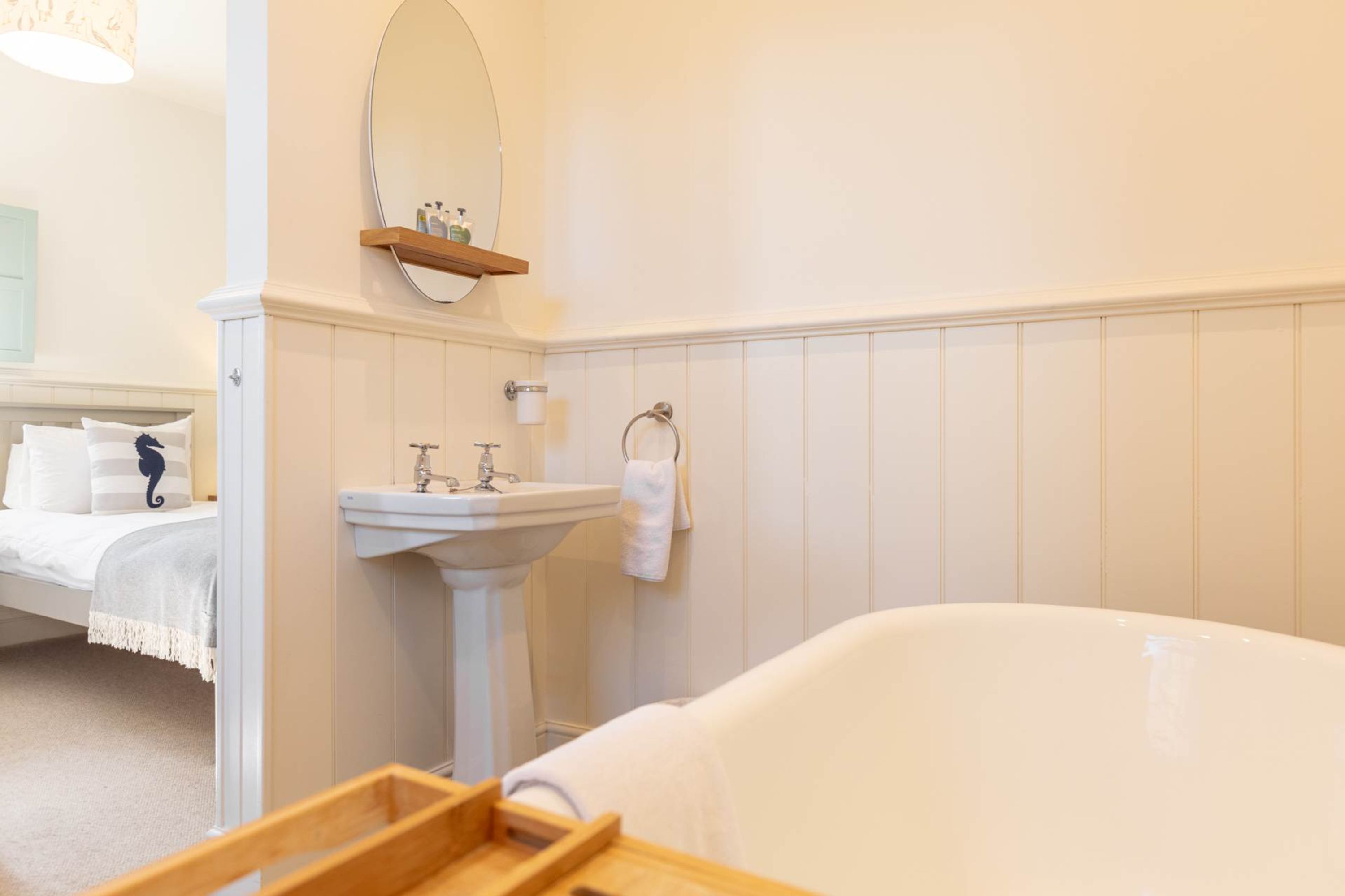 A bathroom with a white sink, a mirror, a towel rack, and a bathtub.