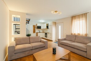 A modern living room with two sofas, a wooden coffee table, and a kitchen in the background. - Lux Suites Leipzig X2 Apartment (Leipzig)