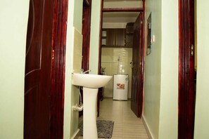 A narrow hallway with a white sink and a water heater. - Lux Suites Momento Apartments Nakuru (Nakuru)