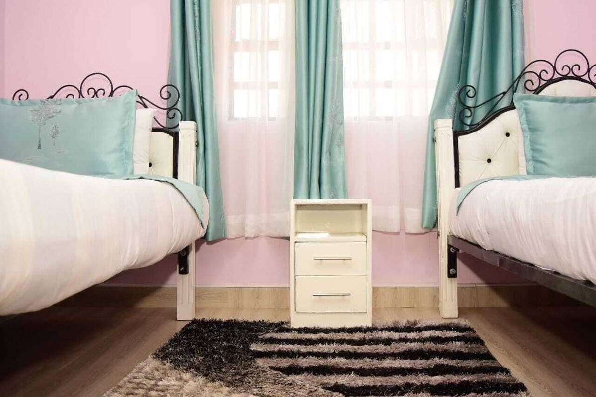 Une chambre avec deux lits, une table de chevet et une fenêtre avec des rideaux.