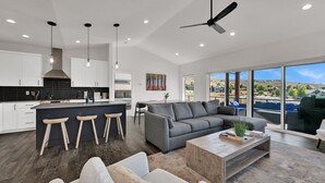 A modern kitchen with a central island, bar stools, and a dining area. - Mountain View Family Retreat w/ Hot Tub & Ski Access (Eden)