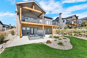 Une maison moderne à deux étages dotée d’un patio, d’un jacuzzi extérieur et d’un jardin aménagé.