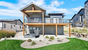 A modern two-story house with a covered patio, a stone retaining wall, and a well-maintained lawn. - Mountain View Family Retreat w/ Hot Tub & Ski Access (Eden)