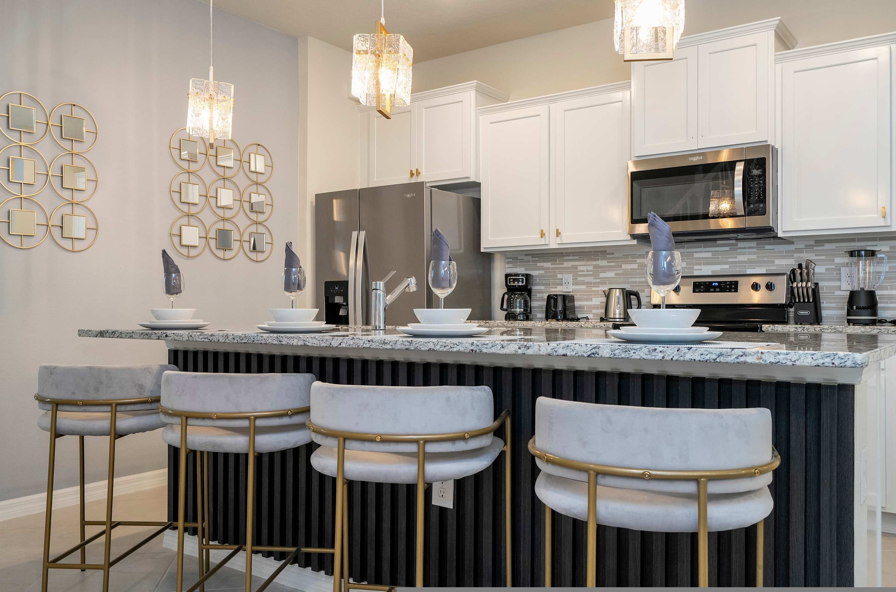 A modern kitchen with white cabinets, stainless steel appliances, and a central island with bar stools.