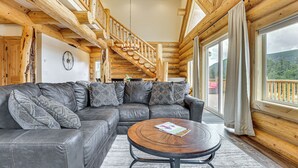 A wooden interior with a leather sectional sofa, a round coffee table, and a staircase leading to a balcony. - Log Cabin w/ Wraparound Deck in Breckenridge! (Breckenridge)