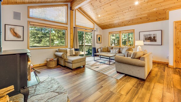 Una sala de estar acogedora con chimenea, ventanas amplias y un techo alto de madera.