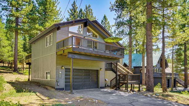 Eine zweistöckige Holzhütte mit Balkon, Garage und einer Treppe, die zum Obergeschoss führt.