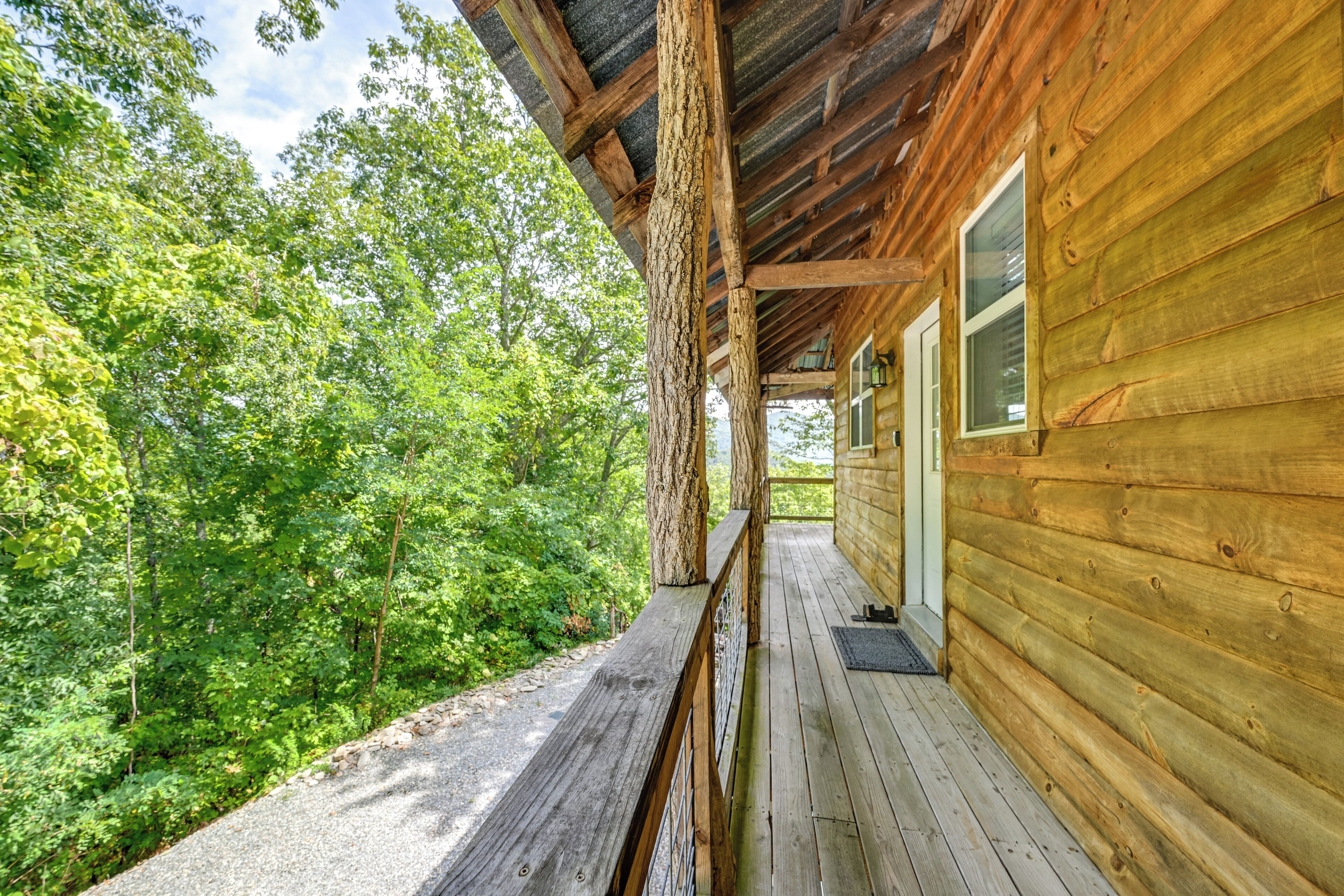 A wooden cabin with a porch overlooking a forested area.