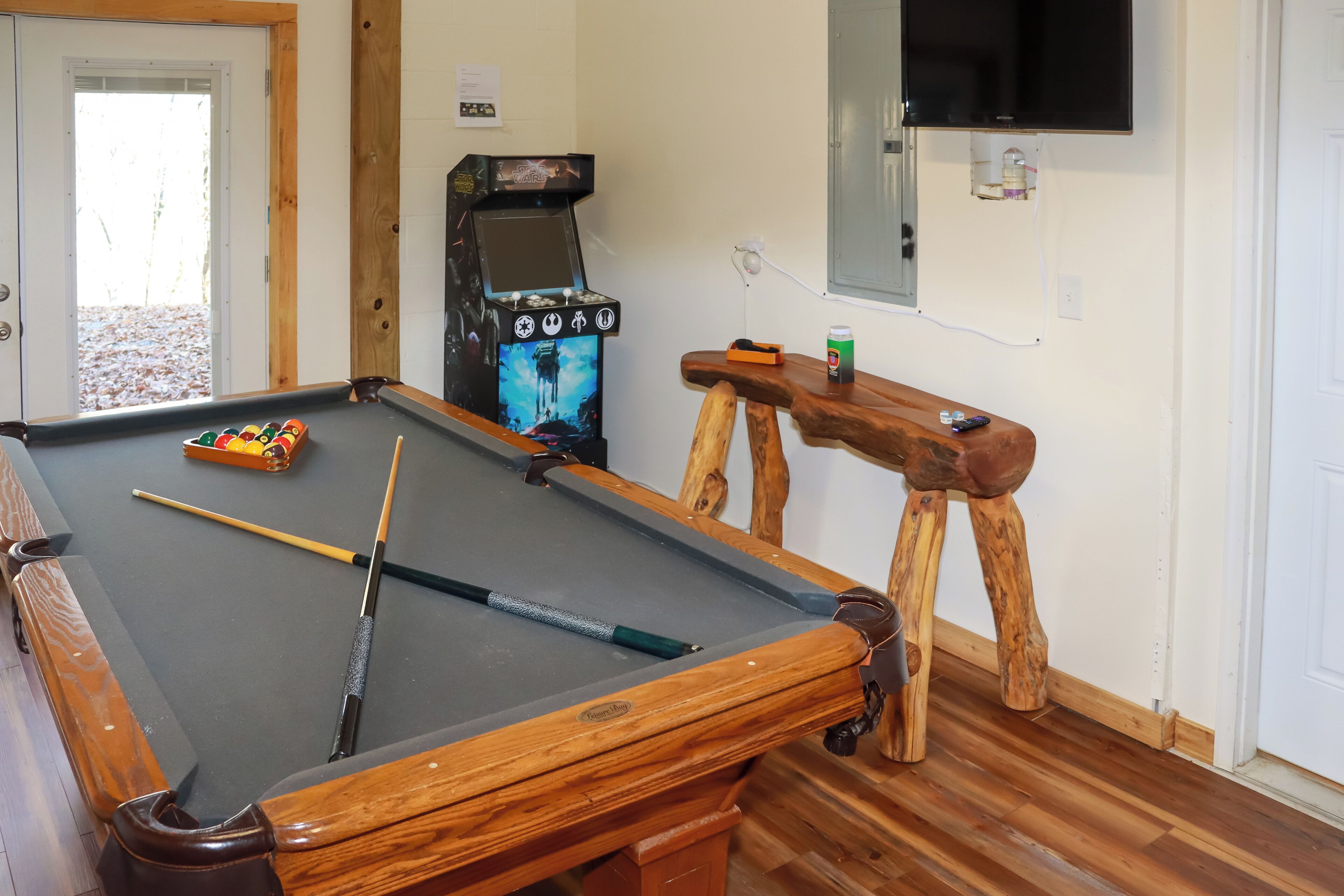 A pool table with a pool cue, a pool ball rack, and a pool table stool.