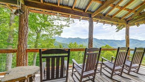 A wooden deck with rocking chairs and a table, overlooking a mountainous landscape. - Bryson City Cabin: Hot Tub + Mtn View! (Bryson City)