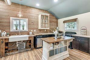 A kitchen with wooden walls, a farmhouse sink, and a central island.