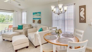 A spacious living room with a dining area, featuring a ceiling fan, a chandelier, and a large window with curtains. - Screened Porch & Community Perks: Myrtle Beach Gem (Myrtle Beach)