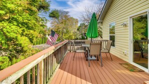 Eine Holzterrasse mit Tisch, Stühlen, einer amerikanischen Flagge und einem grünen Sonnenschirm.