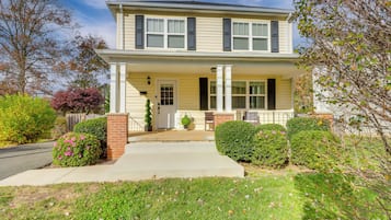 Stunning two-story house with a central entrance, flanked by columns and a small porch.