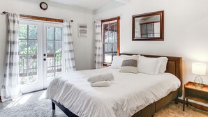A bedroom with a large bed, a wooden headboard, a bedside table with a lamp, and a window with curtains. - Idaho Family Home ~ 11 Mi to Lake Pend Oreille (Cocolalla)