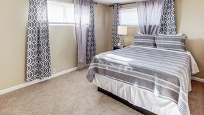 A bedroom with a bed, curtains, a nightstand, and a lamp. - Carlsbad Home ~ 22 Mi to Nat'l Park! (Carlsbad)
