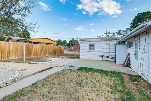 A residential backyard with a wooden fence, a small shed, and a house with a satellite dish.