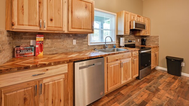 A kitchen with wooden cabinets, a dishwasher, a microwave, and a trash can. - Hopkinsville Home: Walk to Downtown! (Hopkinsville)