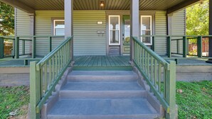 A front view of a building with a green porch, a set of stairs, and a door with a window above it. - Hopkinsville Home: Walk to Downtown! (Hopkinsville)