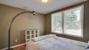A bedroom with a bed, a nightstand, a lamp, and a window with blinds. - Hopkinsville Home: Walk to Downtown! (Hopkinsville)