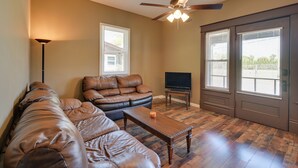 A living room with a leather sectional sofa, a wooden coffee table, a ceiling fan, and a television. - Hopkinsville Home: Walk to Downtown! (Hopkinsville)