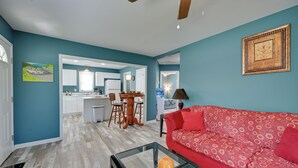 A living room with a red sofa, a glass coffee table, and a dining area with a wooden table and chairs. - Hopkinsville Home Near Parks & Museums! (Hopkinsville)