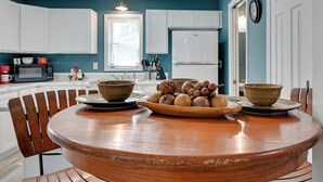 A kitchen with white cabinets, a wooden dining table, and a bowl of nuts. - Hopkinsville Home Near Parks & Museums! (Hopkinsville)