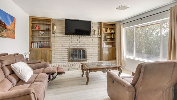Een woonkamer met een open haard, een televisie en een groot raam.
