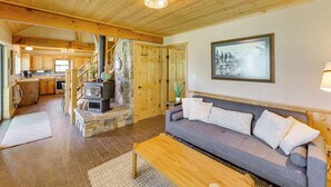 A cozy living room with a stone fireplace, a sofa, and a wooden ceiling. - Mountain-view Ranch w/ 200 Acres in Angel Fire (Angel Fire)
