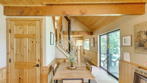 A wooden interior with a staircase, a dining table with chairs, and a large window. - Mountain-view Ranch w/ 200 Acres in Angel Fire (Angel Fire)