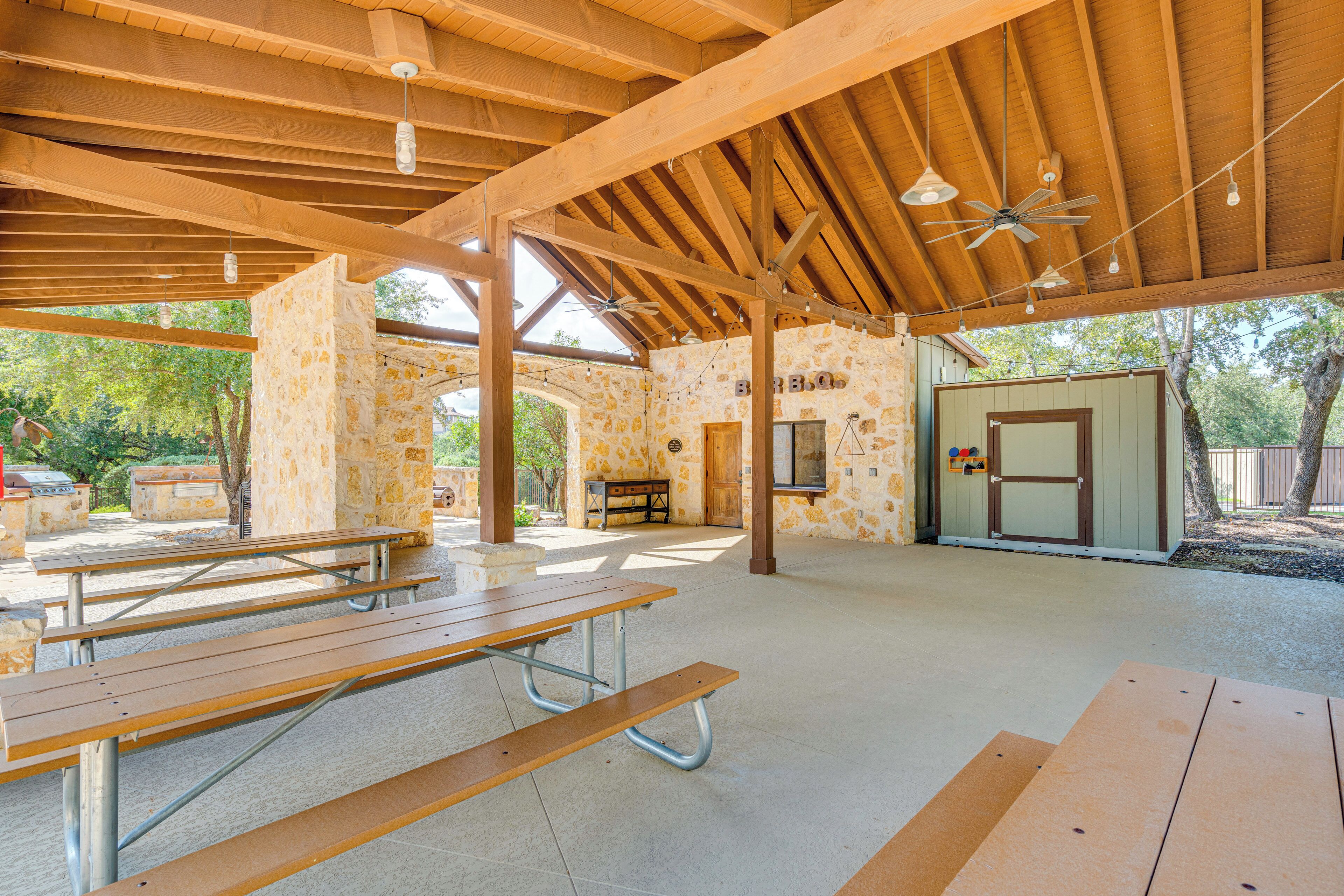 An outdoor covered picnic area with picnic tables and a stone wall.
