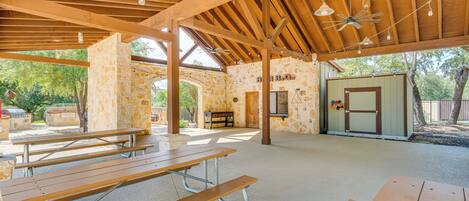 An outdoor covered picnic area with picnic tables and a stone wall.