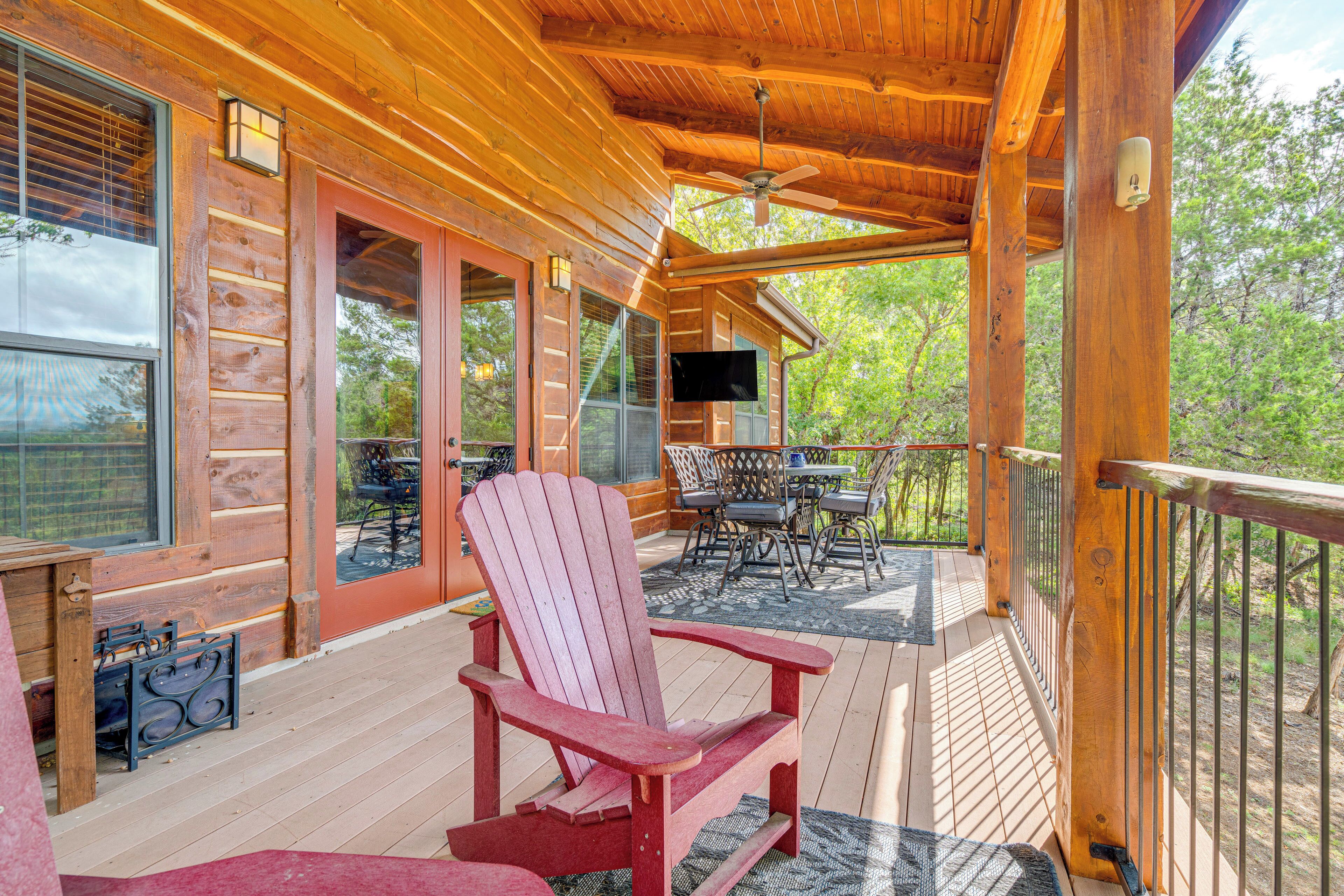 Una terraza de madera con una silla Adirondack roja, una mesa y sillas.
