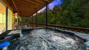 A hot tub on a wooden deck with a view of a forested area.