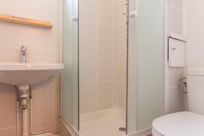 Une salle de bain avec une douche à parois de verre, un lavabo et des toilettes.