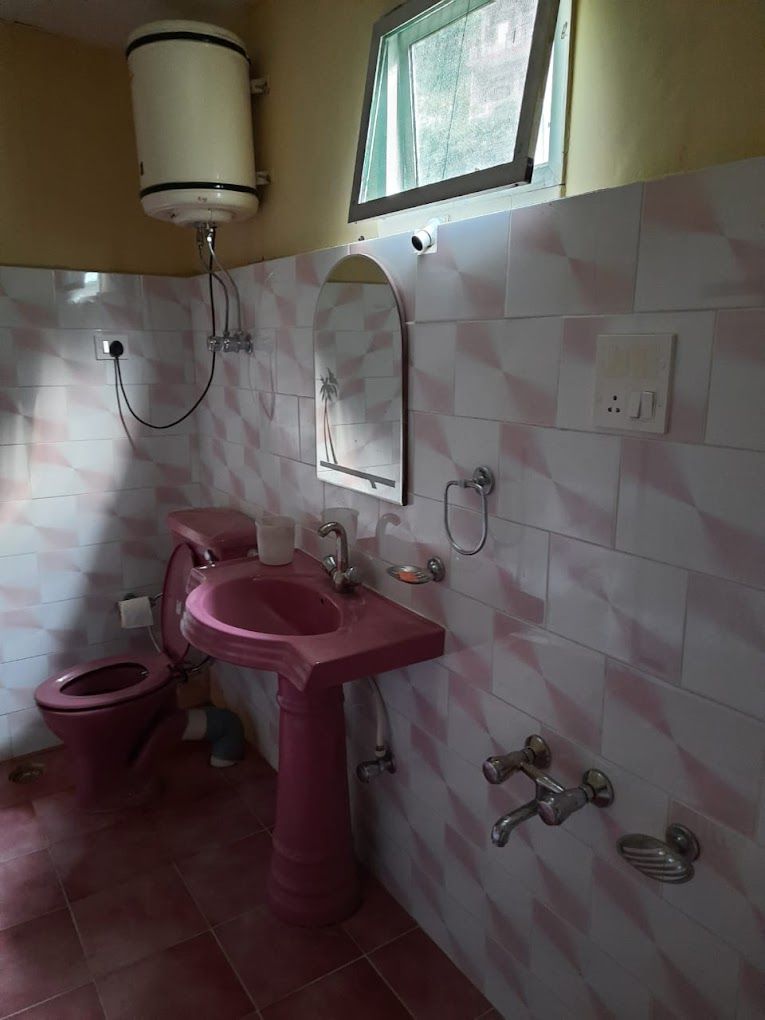 Un baño con lavamanos, inodoro y espejo rosados.