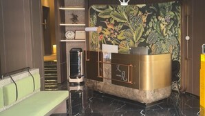 A reception area with a bench, a reception desk, a clock, and a wall with a floral pattern. - Youjian Hotel (Harbin Acheng Impression City) (Harbin)