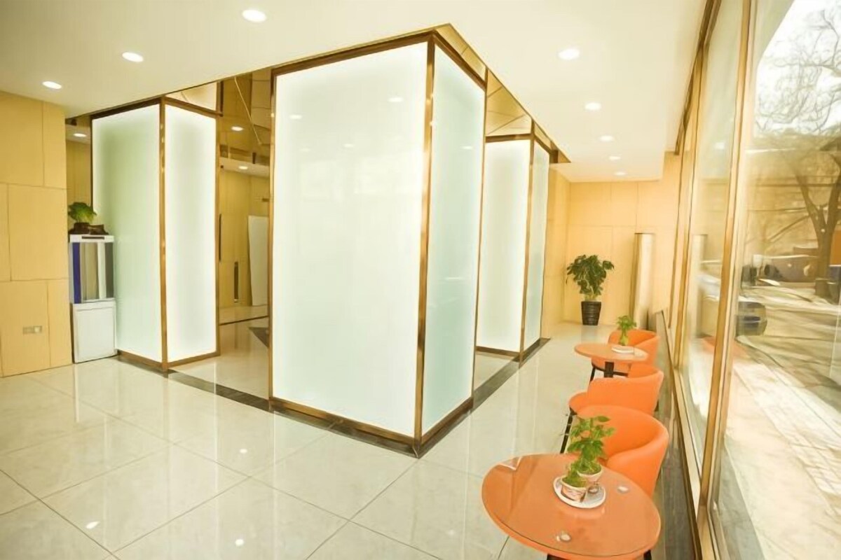 Un interno moderno con reception, pareti divisorie in vetro e un'area salotto con poltrone arancioni.