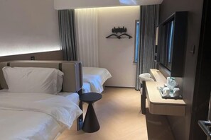 A hotel room with two beds, a desk with a chair, a flat-screen TV, and a mirror.