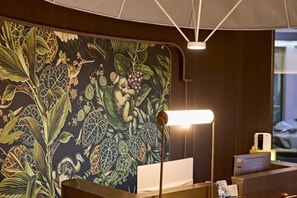 A reception desk with a mural, a desk lamp, and a computer monitor. - Youjian Hotel (Harbin Acheng Impression City) (Harbin)