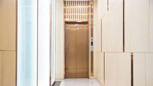 A modern elevator with a sleek design, a control panel, and a lighted panel on the wall.