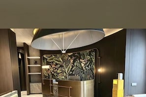 A reception area with a modern design, including a reception desk, a wall with a floral pattern, and a large overhead light fixture.