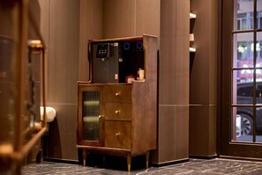 Un vestíbulo de hotel con un mueble de madera, dispensador de agua y un ventanal grande.