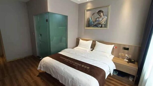 A hotel room with a bed, a nightstand, a wardrobe, and a painting on the wall. - Youjian Hotel (Harbin Acheng Impression City) (Harbin)