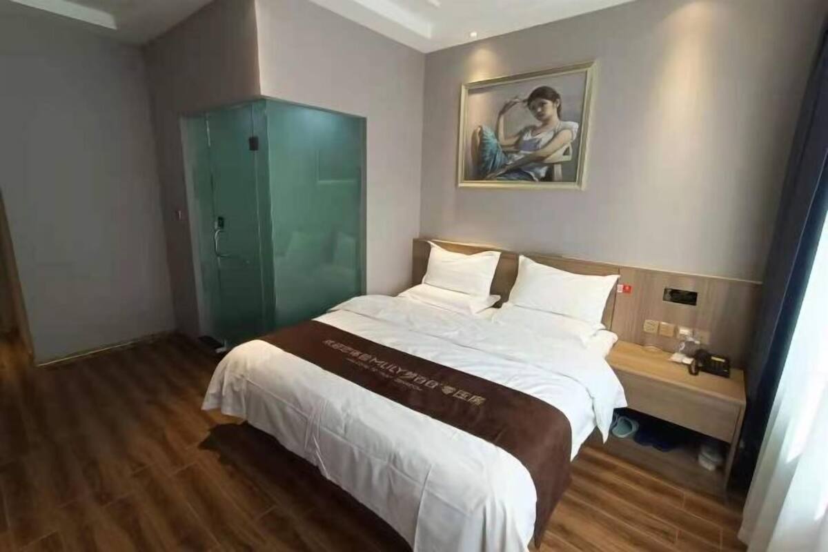 A hotel room with a bed, a nightstand, a wardrobe, and a painting on the wall.