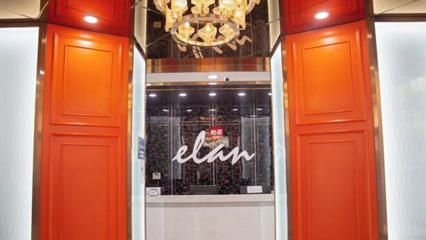 A hotel entrance with a prominent 'elan' sign, a chandelier, and a glass wall.